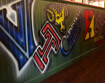 Wall displaying spray paint artwork of local college logos